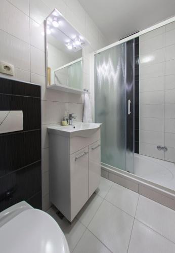 a white bathroom with a sink and a shower at Guesthouse Villa Klara in Baška Voda