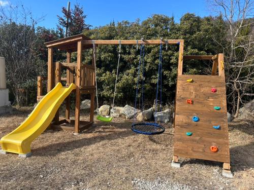 a wooden playground with a slide and a swing at Ｋ&Ｂグランピング　天空の城 in Takeda