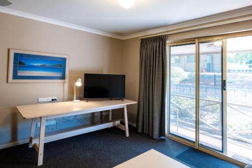 a room with a desk with a tv and a window at Grandis 35 in Albany
