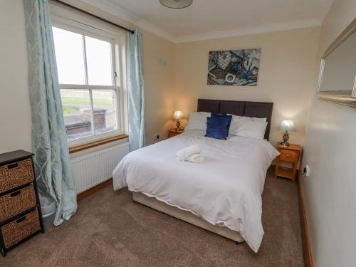 a bedroom with a large white bed and a window at Home Stead Cottage in Embleton