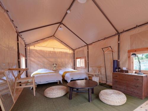 a room with two beds and a table in a tent at 古民家宿rootfield in Shōji