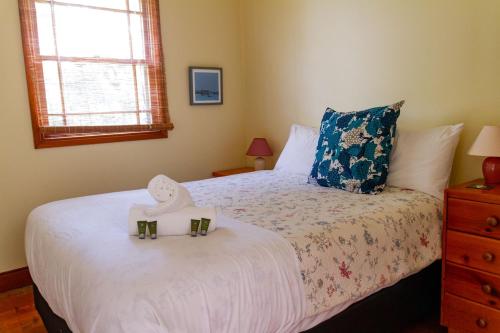 a bedroom with a bed with a hat on it at Cliff Cottage - Noraville in Norah