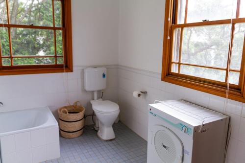 a bathroom with a toilet and a washing machine at Cliff Cottage - Noraville in Norah