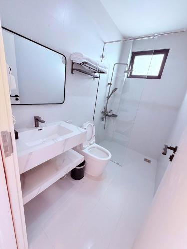 a white bathroom with a sink and a toilet at The SunHill in Da Lat