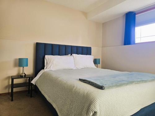 a bedroom with a large bed with a blue headboard at Quaint Lonsdale Suite in Red Deer