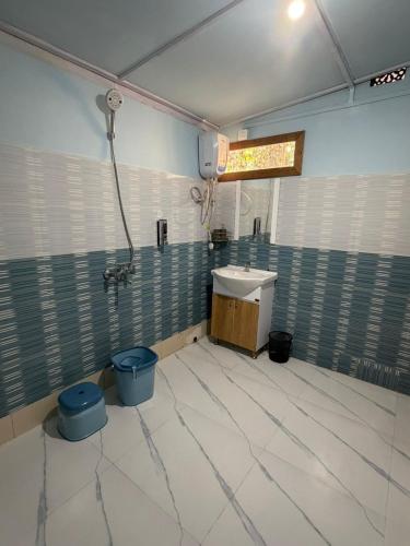 a bathroom with a sink and two blue buckets at Vina Homestay in Jorhat
