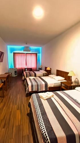 three beds in a room with blue lights at Hotel Pacífico Talara in Talara