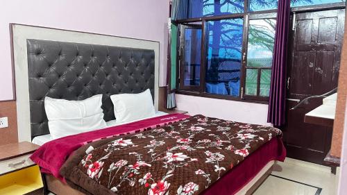 a bedroom with a bed with a red blanket and a window at Krishna Holiday Guest House in Dharmsāla