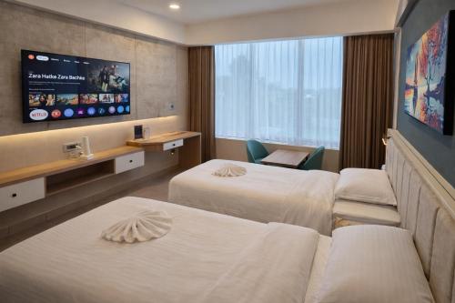 a hotel room with two beds and a flat screen tv at MoonBasa Boutique Hotel and Spa Infopark , Kakkanad in Cochin