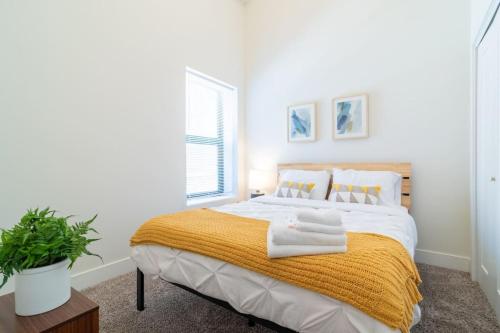 a white bedroom with a bed with a yellow blanket at McCormick Place 420 Friendly 3BR in Downtown Chicago with Optional Parking Sleeps 8 Guests Near Soldier Field, Grant Park and Lakefront Trail in Chicago