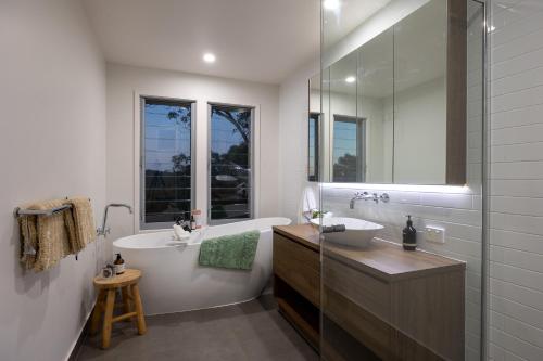a bathroom with a tub and a sink and a mirror at Hinterland Dreamers Poolside Retreat in Yandina Creek