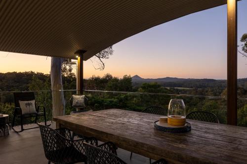a wooden table with a glass of wine on a patio at Hinterland Dreamers Poolside Retreat in Yandina Creek
