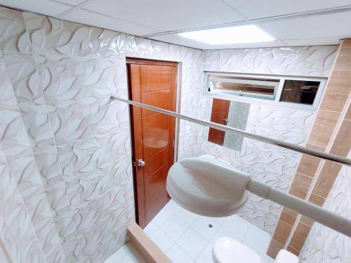 a white bathroom with a toilet and a window at Hospedaje ANDRES & COCHERA in San Antonio