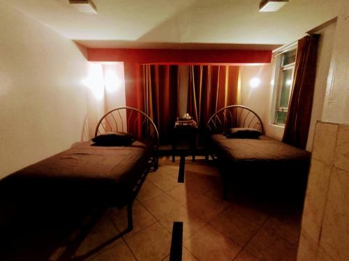 a room with two beds and a window at Hospedaje ANDRES & COCHERA in San Antonio