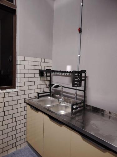 a kitchen with a sink and a white tiled wall at Ayla Hostel at MITC in Ayer Keroh
