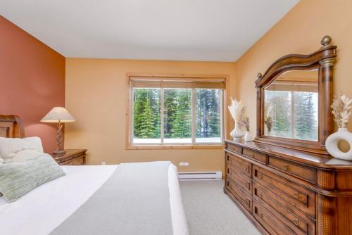 a bedroom with a large bed and a dresser with a mirror at Best Ski-in out 3 Bdrm Chalet, with Hot Tub in Big White