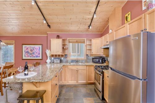 a kitchen with wooden cabinets and a stainless steel refrigerator at Best Ski-in out 3 Bdrm Chalet, with Hot Tub in Big White