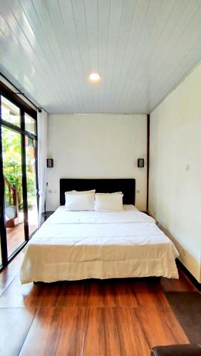 a bedroom with a large bed with a wooden floor at Ratu Roso Resort in Malang