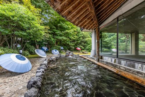 a house with a pond with umbrellas in it at KAMENOI HOTEL Akita Yuze in Kazuno