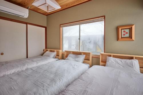 two beds in a room with a window at holidayhouse SERENADE in Nasu