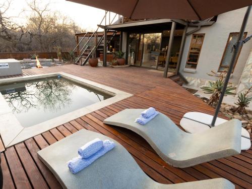 a pool with two lounge chairs and towels on a deck at Ntoma House in Hoedspruit