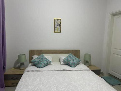 a bedroom with a bed with two tables and two lamps at MySuiteStays Keyless 3Bed Apt in Sacre Coeur in Dakar