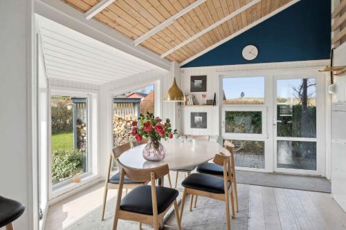 a dining room with a table and chairs and windows at Summer House With Sauna Near Følle Strand in Rønde