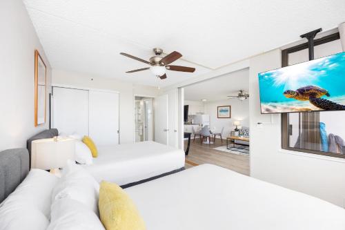 a living room with two beds and a flat screen tv at Warm Aloha Vibes, Mountain Views, Short Walk to Beach, and Free Parking in Honolulu