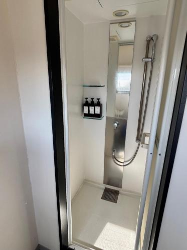 a shower with a glass door in a bathroom at Book Tea Bed IZUOSHIMA in Oshima
