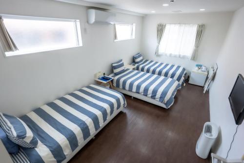 two beds in a room with two windows at Shima Stay holoholo in Zamami