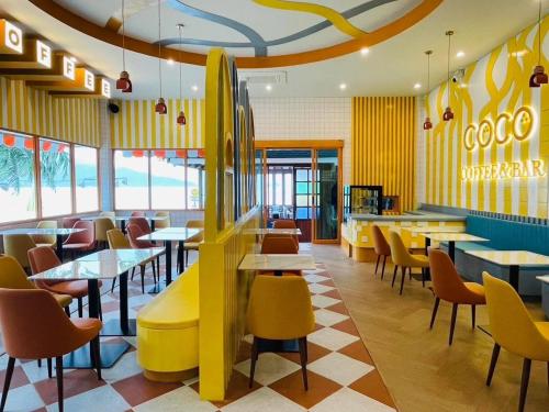 a restaurant with tables and chairs and a restaurant with yellow walls at Coconut Beach Resort, Koh Chang in Ko Chang