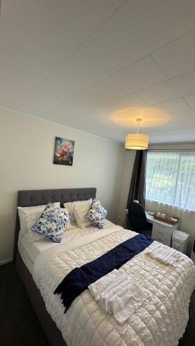 a bedroom with a bed with blue and white pillows at Sochi A double bed Room in a nice home in Upper Hutt