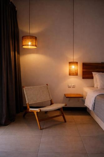 a bedroom with a bed and a chair and lights at Karma Kayak in Gili Trawangan