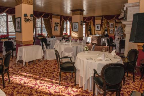 un comedor con mesas y sillas con mantel blanco en Grand Hôtel du Golf & Palace, en Crans-Montana