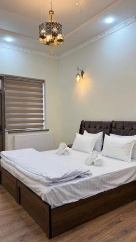 a bedroom with a bed with white sheets and a chandelier at Al Fayz Boutique in Bukhara