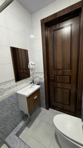 a bathroom with a toilet and a sink and a wooden door at Al Fayz Boutique in Bukhara