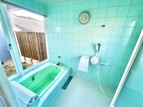 a bathroom with a green tub and a window at Waterfront Hideaway in Miyazaki