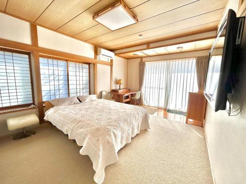 a bedroom with a large bed and a flat screen tv at Waterfront Hideaway in Miyazaki