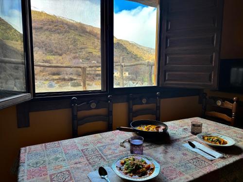 a table with two plates of food and two windows at CASA RURAL CORTIJO MOLINO ALTERO in Trevélez