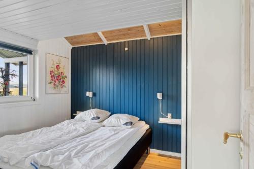 a bed in a room with a blue wall at Summer House With Sauna Near Følle Strand in Rønde