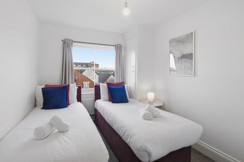 two twin beds in a room with a window at Modern Serviced Apartments Steps From Gloucester Quays in Gloucester