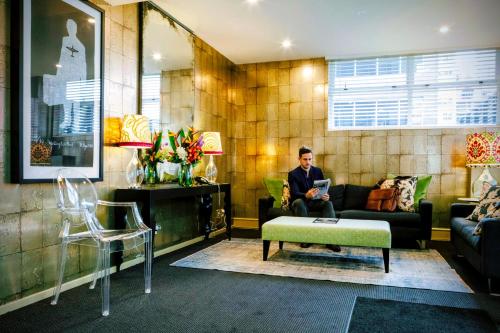 a man sitting on a couch in a living room at Gilmer Apartment Hotel in Wellington