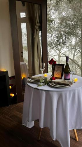 a table with a white table cloth and a bottle of wine at Cabaña Sendero De Las Luciernagas in Zacatlán
