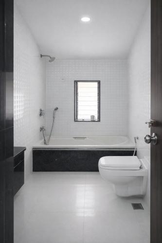 a white bathroom with a tub and a toilet at Hangout Villa in Malavli