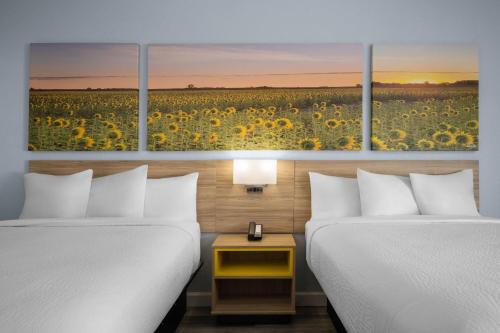 a hotel room with two beds and a field of sunflowers at Days Inn by Wyndham Dodge City in Dodge City