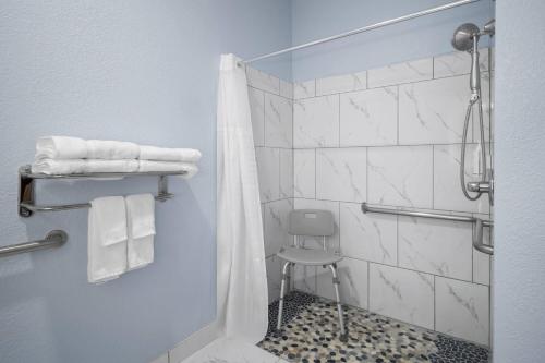 a bathroom with a shower with a stool and towels at Days Inn by Wyndham Dodge City in Dodge City