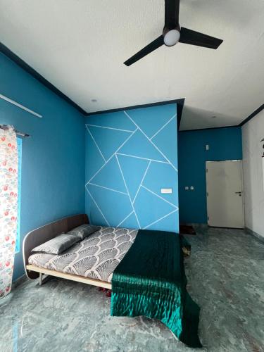 a bedroom with a blue wall with a bed and a ceiling fan at Chamundi Temple-Hill View in Mysore