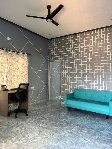 a living room with a blue couch and a ceiling fan at Chamundi Temple-Hill View in Mysore