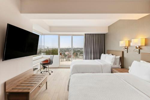 a hotel room with two beds and a flat screen tv at Fiesta Inn Express Ciudad de México Forum Buenavista in Mexico City