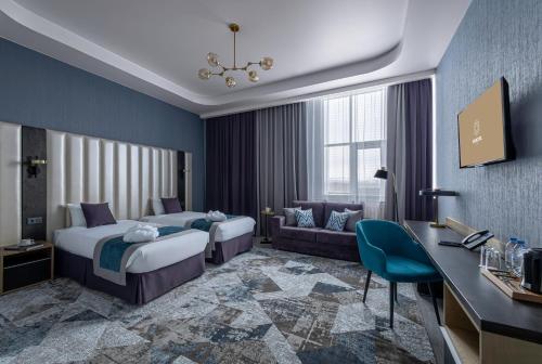 a hotel room with two beds and a couch at Monotel Hotel in Ustʼ-Kamenogorsk